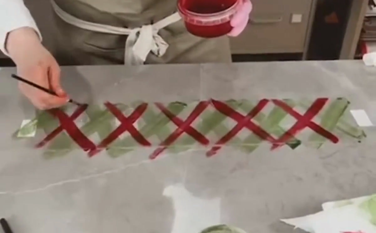 Olga Penioza applies colored cocoa butter in crosswise strokes to chocolate-transfer film